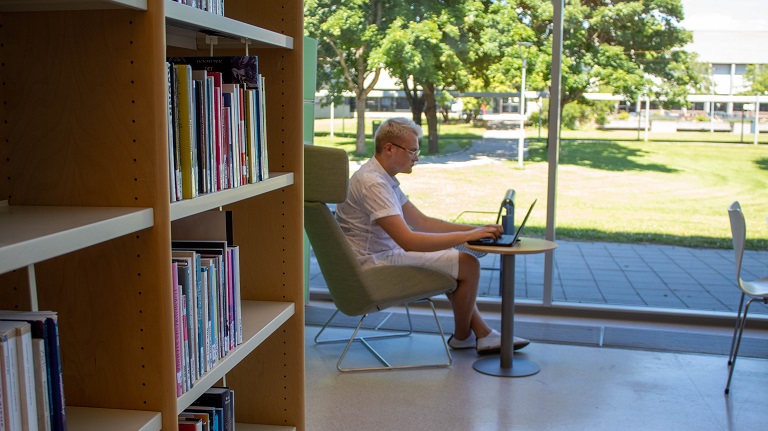 student bruker laptop i bibliotek